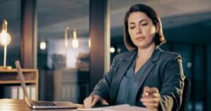 A paralegal reviews documents while seated at a desk with a laptop.